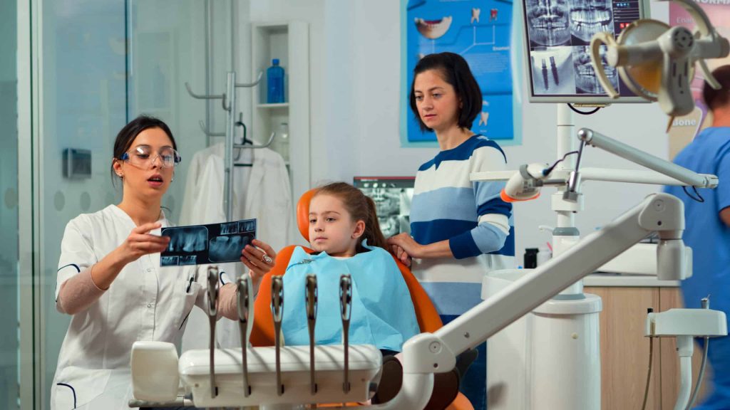 Pediatric woman dentist treating little girl patient in stomatological office
